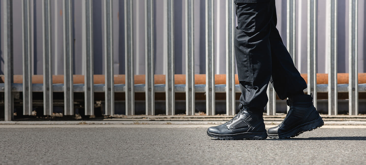 Close-up image of a man walking along a concrete path, wearing a pair of Magnum Spider EXO Boots