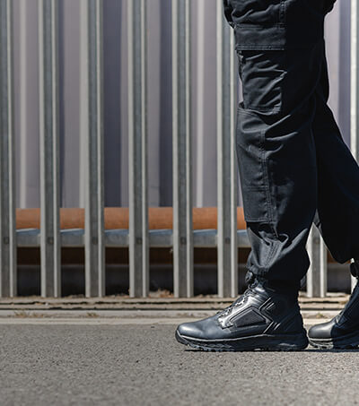 Close-up image of a man walking along a concrete path, wearing a pair of Magnum Spider EXO Boots
